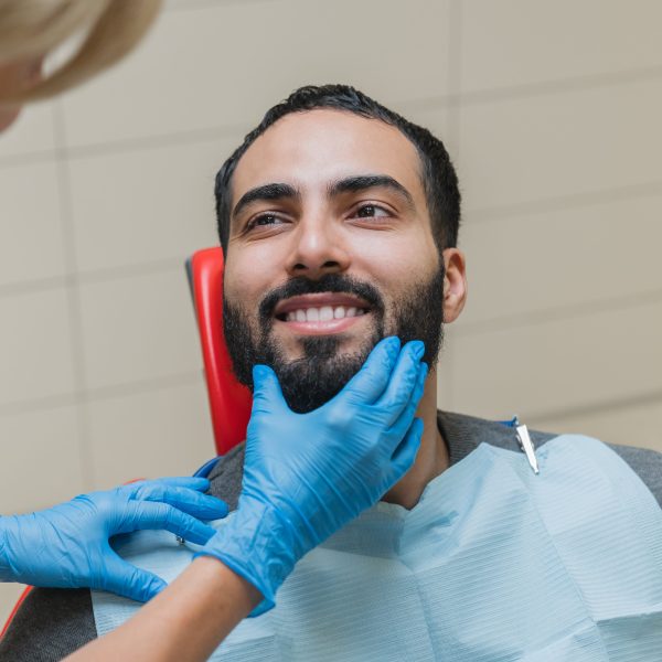 man with perfect smile visiting dentist after getting dental implants to help with gum disease